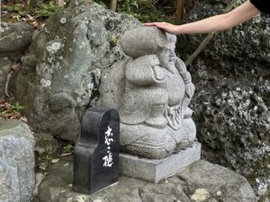 射山神社内の大黒さまの「恋こ槌」に触れる女性
